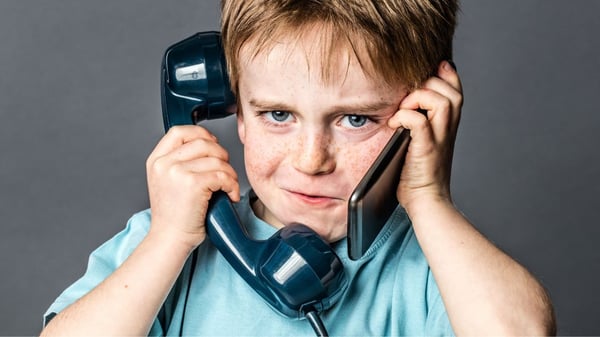 Boy holding landline and mobile phone